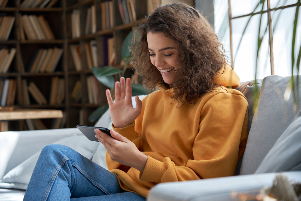 girl sit on sofa at home holding phone