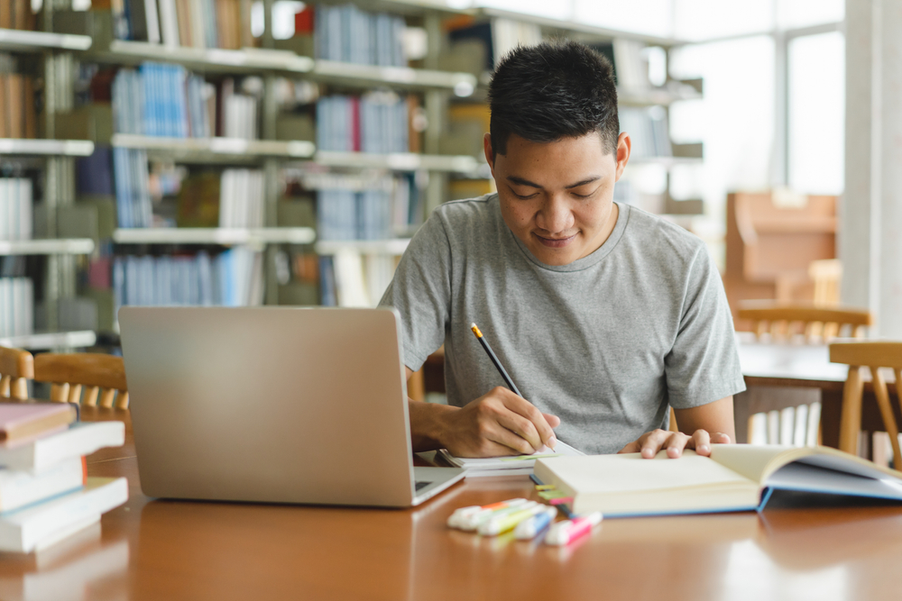 student studying and reading book in library